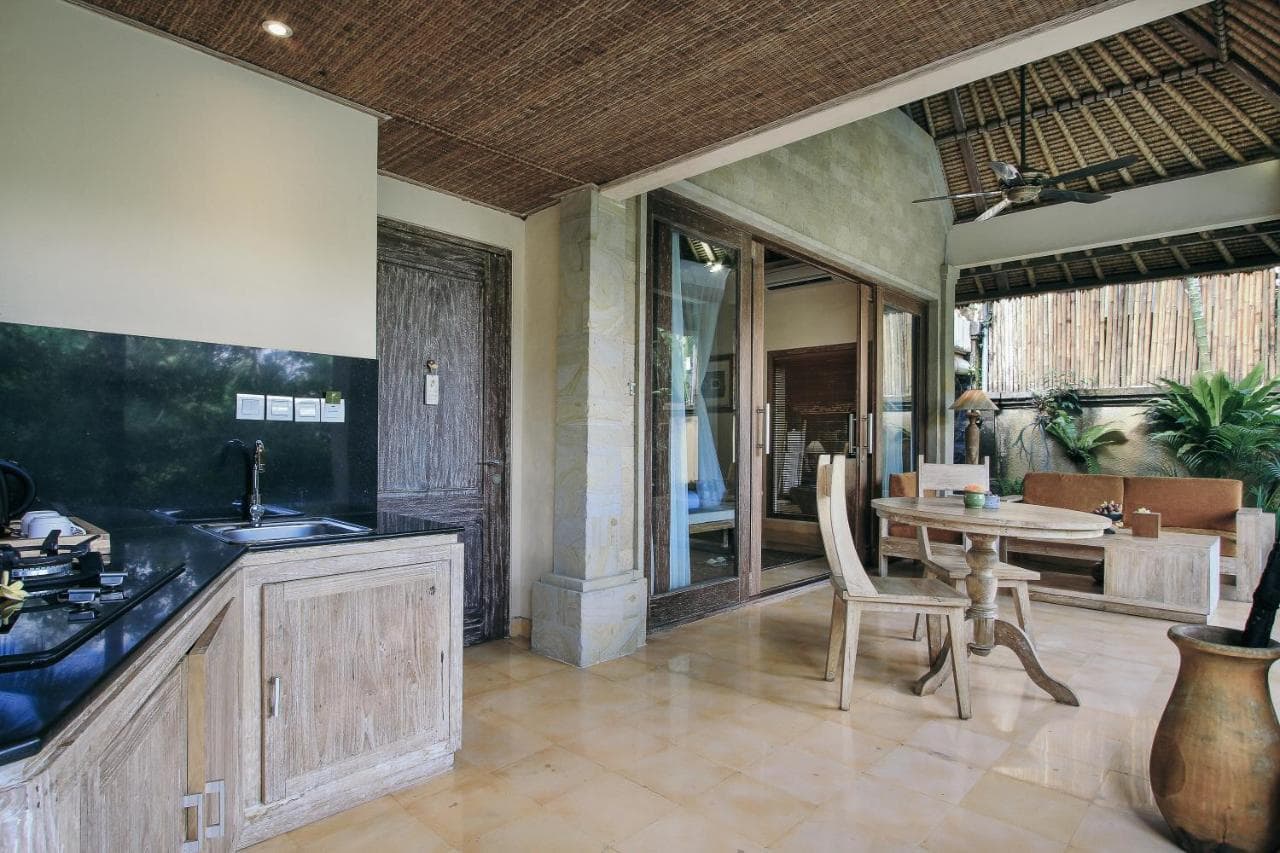 Open-plan kitchen and dining area at The Sankara Resort by Pramana, with wooden cabinetry, dining table, and access to an outdoor terrace
