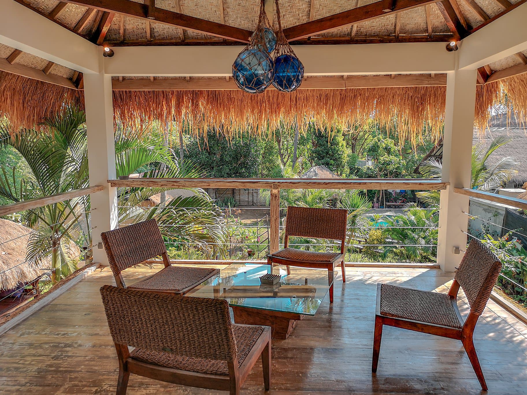 Villa Turkuaz covered lounge area with woven seating, glass table, wooden ceiling beams, and views of tropical vegetation outside