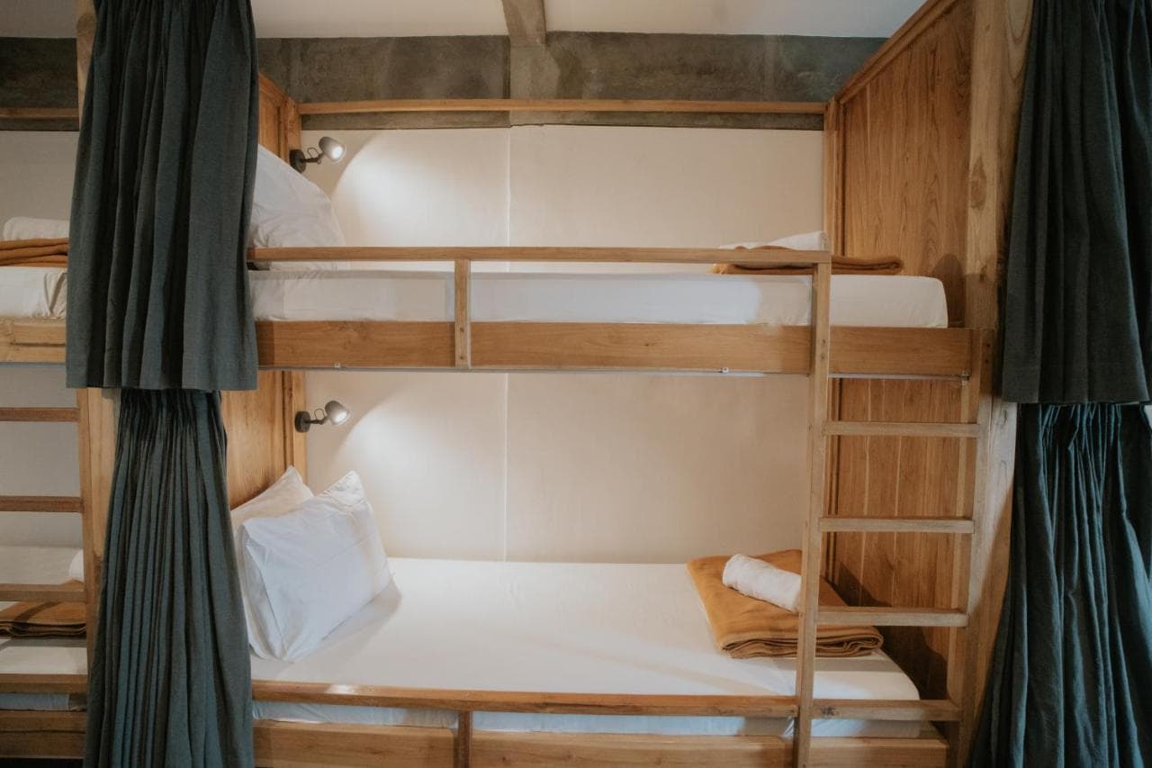 Wooden bunk bed with white bedding and dark green curtains at Green Hill Boutique Hotel