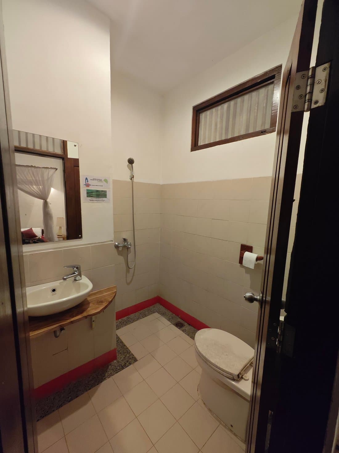 Bathroom at Kelimutu Crater Lakes Ecolodge with sink, toilet, shower, tiled floor and red accent rug