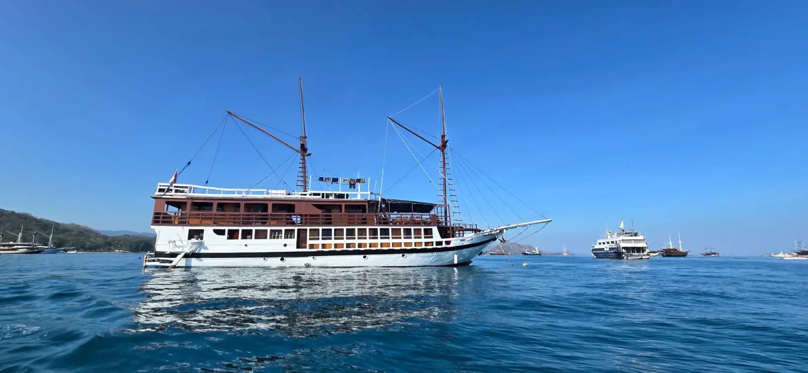Seamore Papua liveaboard anchored on calm blue water with other boats visible in the distance under a clear sky