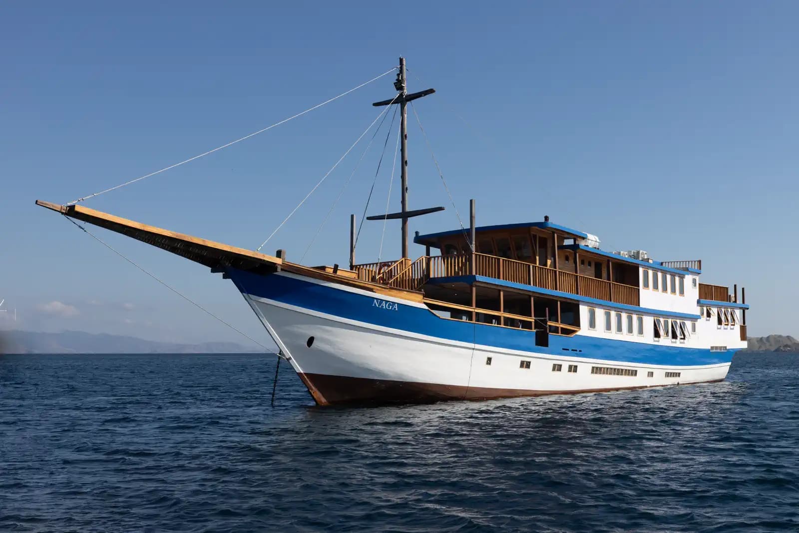Naga Biru, a blue and white phinisi, at anchor