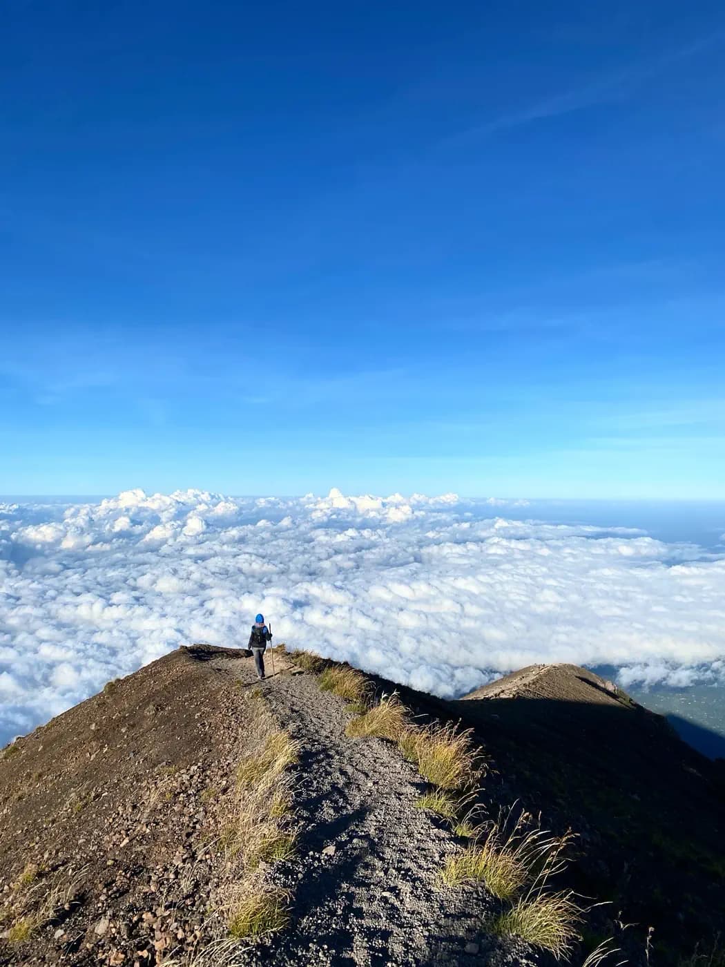 Hikers on the summit ridge of Mount Agung above the clouds at sunrise