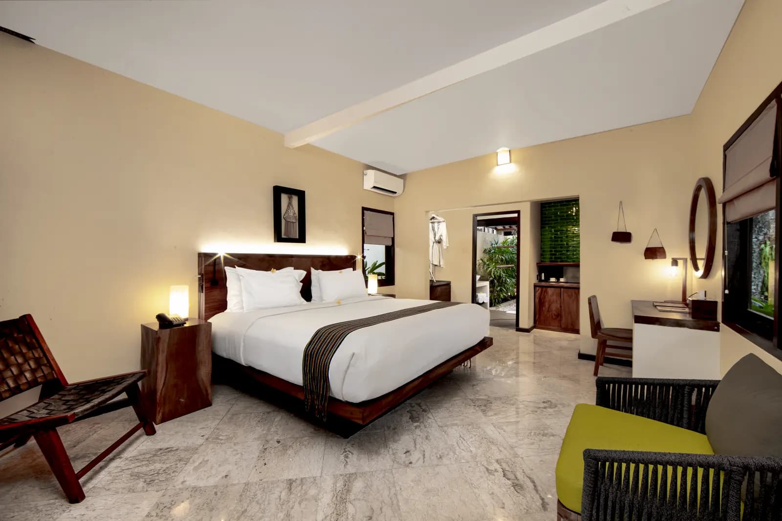 Spacious bedroom at Qunci Villas with king bed, dark wood furniture, pale yellow walls, marble floor, and en-suite bathroom visible through open door