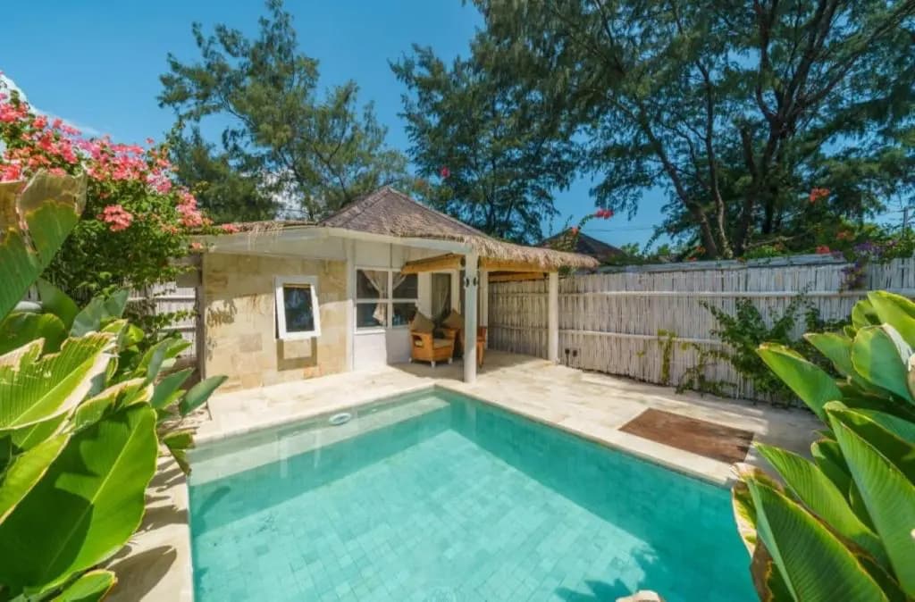 ORA Resort Gili Meno pool area with stone deck, wooden pavilion, planted garden borders, and wooden fence