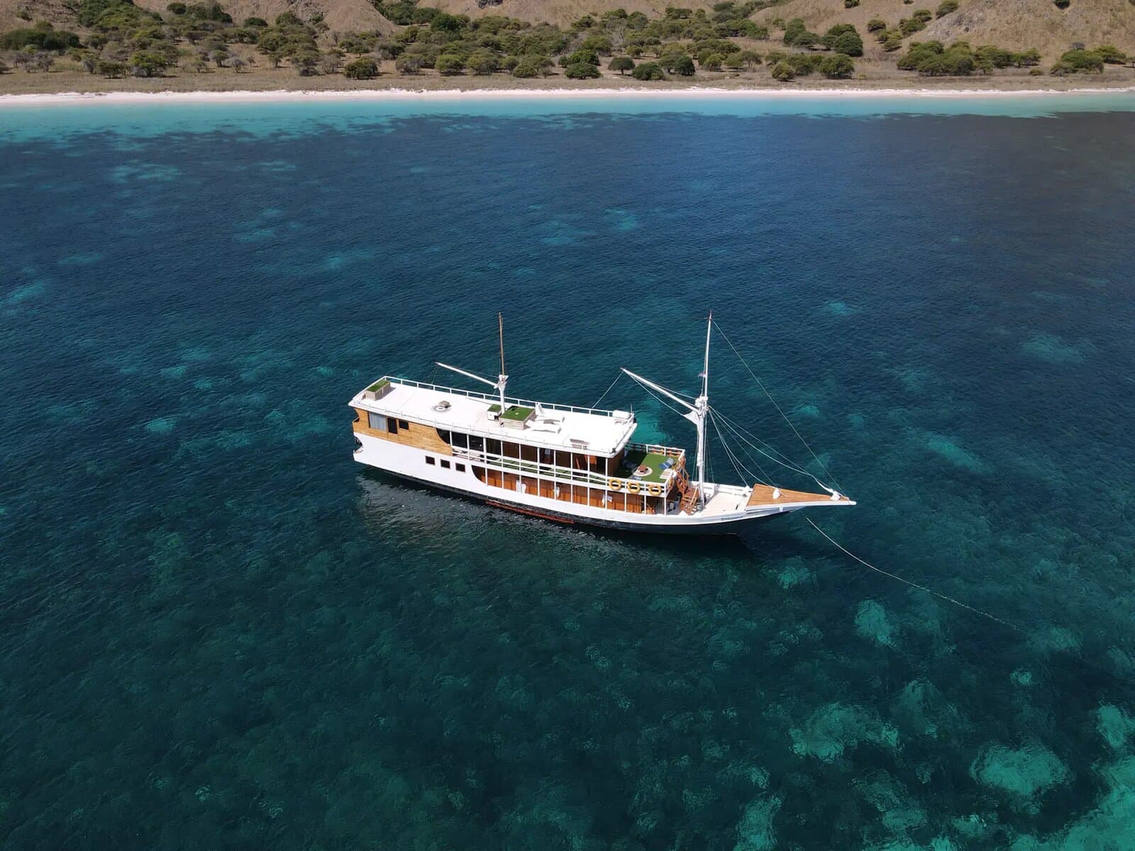 Dinara phinisi anchored over a reef in Komodo National Park